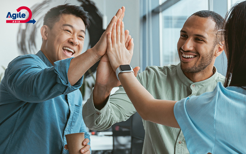 Happy agile team high-fiving at work.